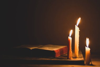 İncil ve eski meşe ahşap bir masa üzerine de mum. Güzel altın arka plan. Din kavramı.