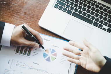 İş dünyası ekibi liderleri, meslektaşlarına sunum ve iş stratejisi üzerinde çalışıyor ve bir tartışma yapıyorlar, grafik ve grafiğe işaret ederek, işbirliği ortaklığının başarısına işaret ediyorlar.