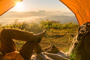 Seyahat bulma kavramı tarafından bir turist çadırda oturan uzun yürüyüşe çıkan kimse adam. Bacaklar görünümünü. Bakış açısı Shot 
