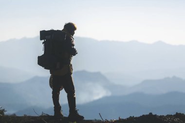 Hipster en yüksek dağında gün batımı zevk sırt çantası olan genç adam. Arka plan Vadisi manzara görünümü mockup üzerinde turist Gezgin. 