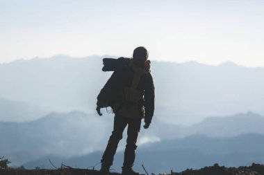Hipster en yüksek dağında gün batımı zevk sırt çantası olan genç adam. Arka plan Vadisi manzara görünümü mockup üzerinde turist Gezgin. 