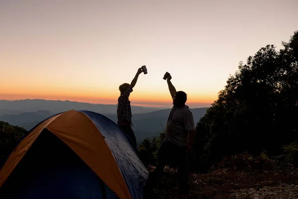 山間地で素晴らしい夕日の空の下で近くのキャンプファイヤーで山の頂上に幸せな 人の男性観光客 — ストック写真
