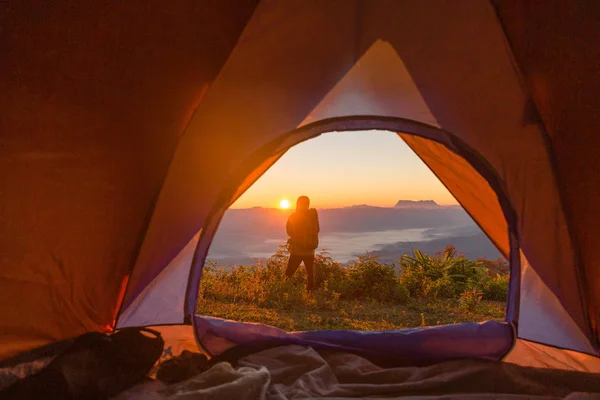ハイカー オレンジ色のテントの近くのキャンプで立ち上がって山中バックパックします 遠くを見ているバックパッカー — ストック写真