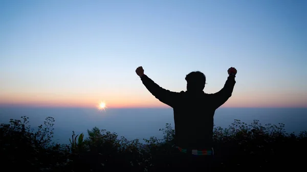 Uomo grato braccia aperte al sorgere del sole in cima alla montagna — Foto Stock