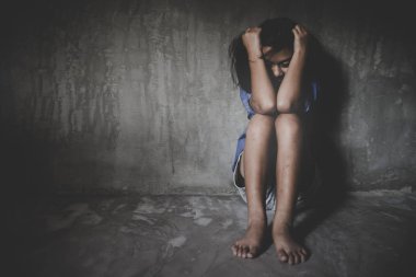 Üzgün küçük kız umutsuzluk içinde duvara karşı oturan. 