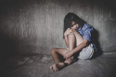 Üzgün küçük kız umutsuzluk içinde duvara karşı oturan. 