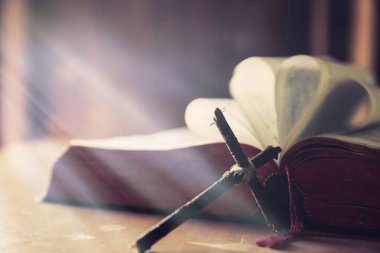 Cross with Bible on a old oak wooden table.  clipart