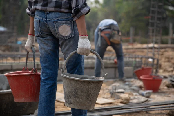 Trabalhador da construção segurando um balde de concreto molhado — Fotografia de Stock