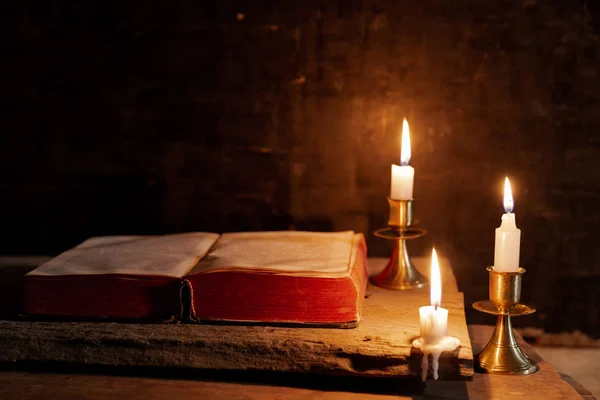 A bible open on a table next to a candle. — Stock Photo, Image