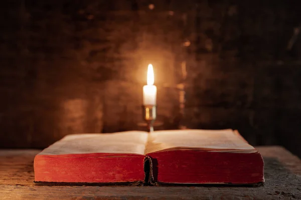 Библия на столе рядом со свечой . — стоковое фото