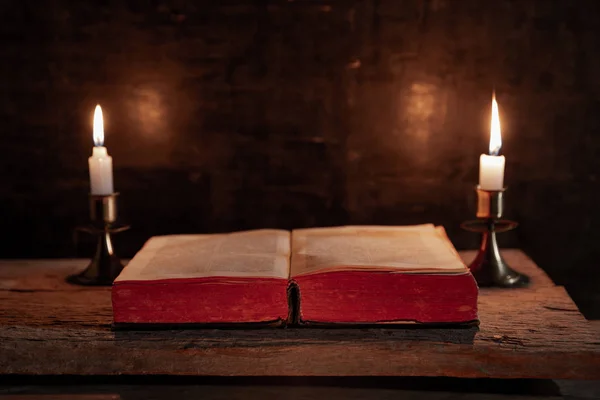 Open Holy Bible and candle on a old oak wooden table. — Stock Photo, Image