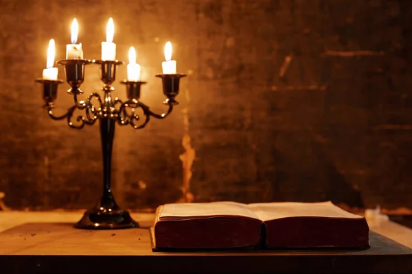 Öppna Bibeln och ljuset på ett gammalt ekträ bord. — Stockfoto