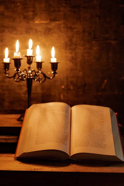 Abra a Bíblia Sagrada e vela em uma mesa de madeira de carvalho velho . — Fotografia de Stock