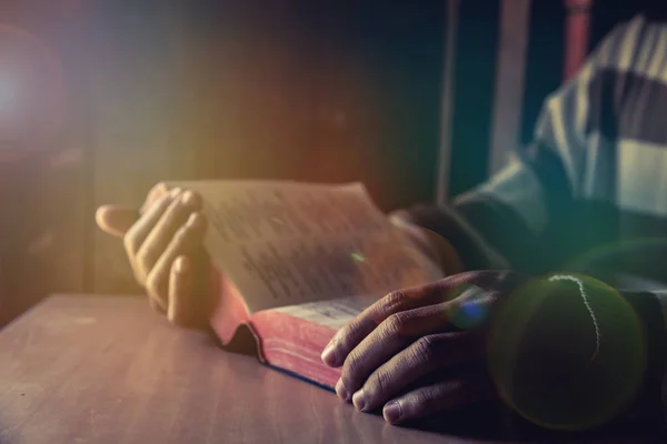 Un hombre sentado mientras lee la Biblia o libro en la habitación — Foto de Stock