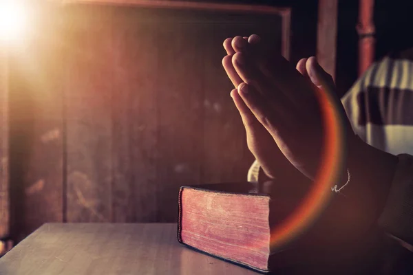 Hands of a person raised together in prayer with bible — Stock Photo, Image