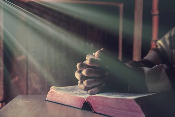 Les mains d'une personne élevée ensemble dans la prière avec la bible — Photo