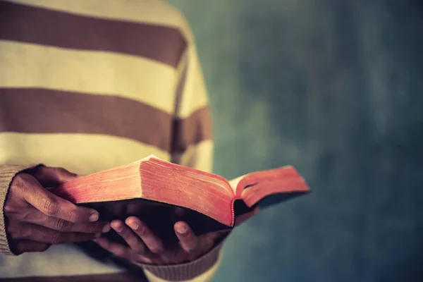 Ein Mann steht beim Lesen von Bibel oder Buch über Betonmauer — Stockfoto