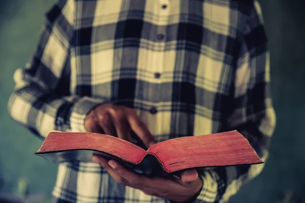 Un uomo in piedi durante la lettura di bibbia o libro su muro di cemento wi — Foto Stock