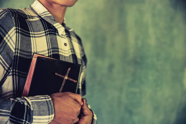 Un joven sosteniendo una Biblia en sus manos — Foto de Stock