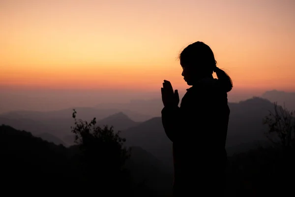 Silhouette of girl praying over beautiful sky background. Christ — Stock Photo, Image