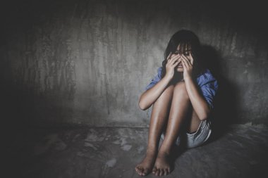 Üzgün küçük kız umutsuzluk içinde duvara karşı oturan. 