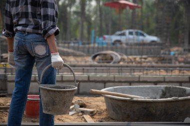 Bir kova ıslak beton tutan inşaat işçisi