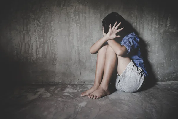 Kleines trauriges Mädchen, das sich im Keller versteckt oder eingesperrt hält. Menschenhandel Stockfoto