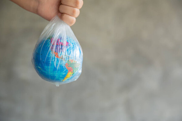 The girl's hand holds the earth in a plastic bag. 