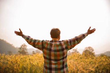 Scott gömlekli genç çiftçi bir tarlada kollarını kaldırdı ayakta 