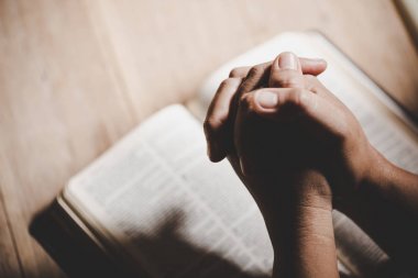 Eller inanç için kilise kavramı bir Kutsal Kitap üzerinde dua katlanmış.