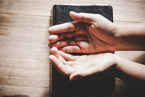 Hands folded in prayer on a Holy Bible in church concept for faith. — Stock Photo, Image