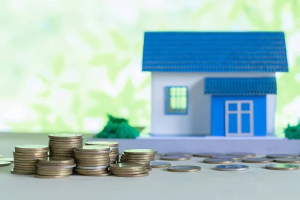 Model of house with coins on wooden table — Stock Photo, Image