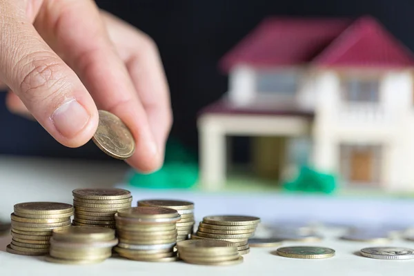 Dům na mince, na které se ženou rukou, plánuje úspory peněz — Stock fotografie
