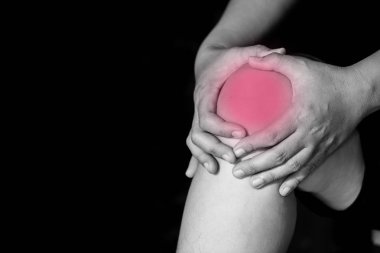 Bir kadın dizini tutarak, kırmızı bir nokta ile diz ağrısı