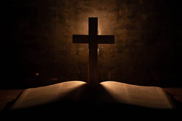 Krzyż z Biblii i świecy na starym drewnianym dębowym stole. — Zdjęcie stockowe