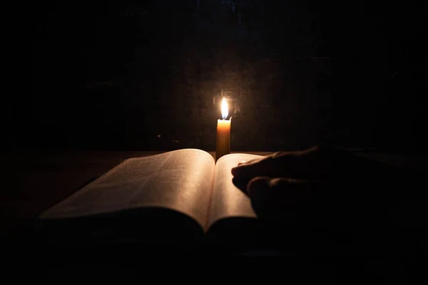 Жінки молитися про Біблію в світлі свічки селективного фокусування. — стокове фото