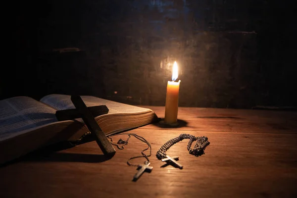 Крест со свечой и библией на деревянном столе из старого дуба . — стоковое фото