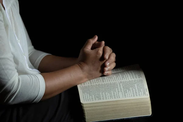 Andlighet och religion, händer vikas i bön på en helig bibl — Stockfoto