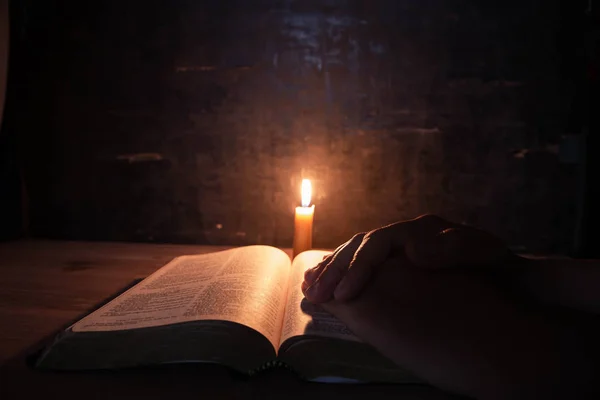 Vrouwen bidden op de Bijbel in het licht kaarsen selectieve focus. — Stockfoto