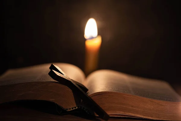Korsa med bibel och ljus på ett gammalt ek träbord. — Stockfoto