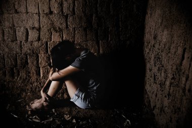 Depresyonda ve umutsuz genç Asyalı kız, genç kadın üzgün, zavallı kız gözaltına alınıyor ve kirli bir zeminde oturuyor..