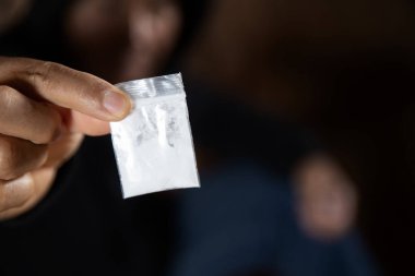 Bir erkek elinde plastik paket ya da torba kokain ya da başka bir uyuşturucu, uyuşturucu bağımlılığı ve tehlike bağımlılığı kavramı taşır.