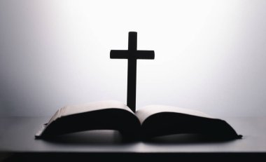 Beyaz Arkaplanda ahşap haçlı İncil. Kutsal kitap. Siyah beyaz fotoğrafçılık. Ahşap haç ahşap masada incili açtı.