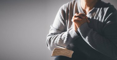 İnanç, maneviyat ve din kavramında kutsal İncil üzerine dua etmek için eller kavuşturuldu. Elinde İncil tutan ve dua eden tanınmamış bir kadın. Kutsal İncil 'e dua ederken ellerimiz birbirine kenetlendi..