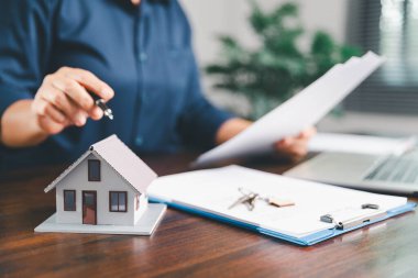 Kadın eli küçük minyatür bir oyuncak evi tutuyor, kendi emlak konseptine taşınma hayalini sembolize eden kadın emlak yatırımını, ipotek planlama, güvenli bir gelecek sigortasını temsil ediyor..