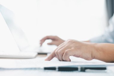 İş finans ve muhasebe kavramı. İşadamı dizüstü bilgisayarla çalışır, mali belgeler ofis masasında, vergi raporlarını analiz eder, bütçe yönetimi ve kurumsal finansal planlamayı doğrulukla yapar.