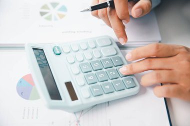 Ofisteki finans raporunu hesaplamak için hesap makinesi kullanan bir muhasebeci. işletme finansmanı, mali belgeleri düzenleyerek vergi hesaplama, gelir yatırımlarını takip etme, elle hesaplama.