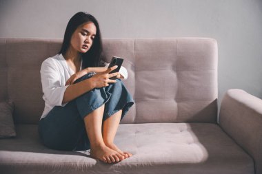 Depresyondaki kadın kanepeye oturur. Kederli insan yalnız başına oturur ve dizlerine sarılır sıkıcı üzgün üzgün sinirli sinirli. Boğucu bir yük altında umut bulmak için mücadele ediyorlar. ruh sağlığı kavramı.