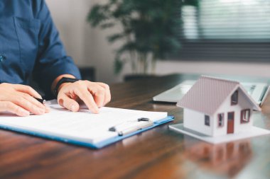 Kadın eli küçük minyatür bir oyuncak evi tutuyor, kendi emlak konseptine taşınma hayalini sembolize eden kadın emlak yatırımını, ipotek planlama, güvenli bir gelecek sigortasını temsil ediyor..