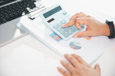 Ofisteki finans raporunu hesaplamak için hesap makinesi kullanan bir muhasebeci. işletme finansmanı, mali belgeleri düzenleyerek vergi hesaplama, gelir yatırımlarını takip etme, elle hesaplama.